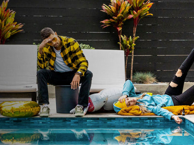 A guy and a girl are hungover and depressed by the pool