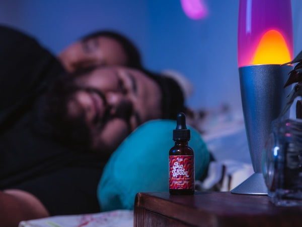 A man is sound asleep next to a bottle of Big Spoon showing the CBD oil benefits for sleep
