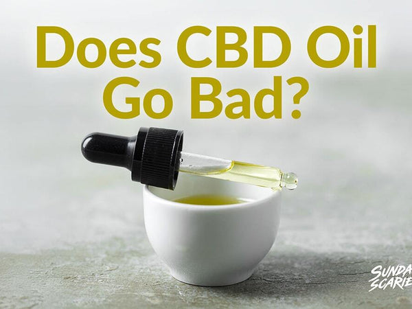 A pipette laying across a cup of yellow oil showing expired CBD oil