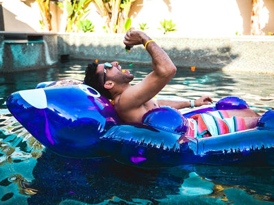 A guy chills on a raft in the pool eating Sunday Scaries and showing how THC gummies make you feel