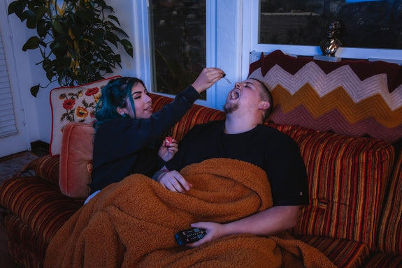 A girlfriend shows her boyfriend how to use CBD oil for sleep before bedtime