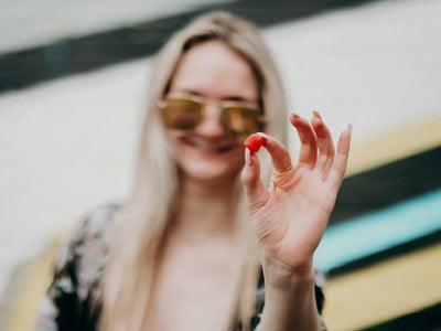 A woman holds up a gummy to show what CBD edibles are