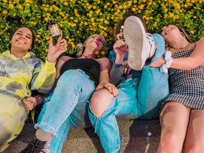 A group of girls lay on the grass laughing holding up a bottle to show what delta-9 gummies are