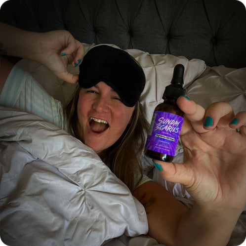 A woman with an eyemask on her forehead takes Sunday Scaries CBN + CBD sleep oil to shut her mind down before bed