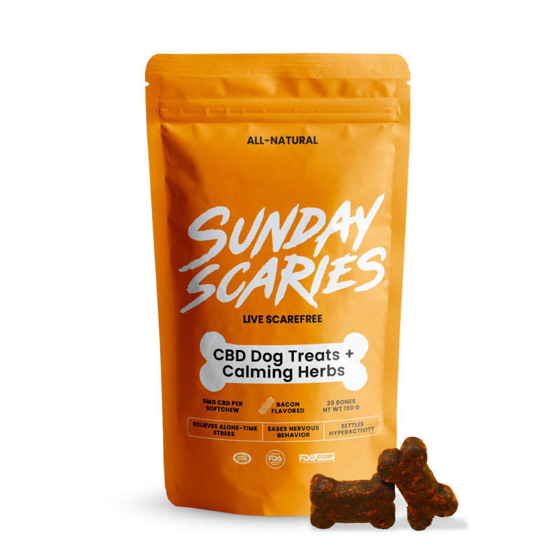 A package of Sunday Scaries CBD dog treats with a bone-shaped soft chew visible in front of the package. The package is orange with white and black text, and the treats are described as non-intoxicating, THC-free with all-natural ingredients.