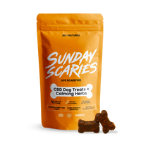 A package of Sunday Scaries CBD dog treats with a bone-shaped soft chew visible in front of the package. The package is orange with white and black text, and the treats are described as non-intoxicating, THC-free with all-natural ingredients.