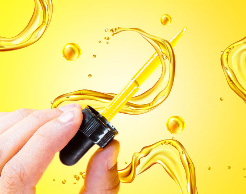 A hand holding a CBD oil dropper on a yellow background