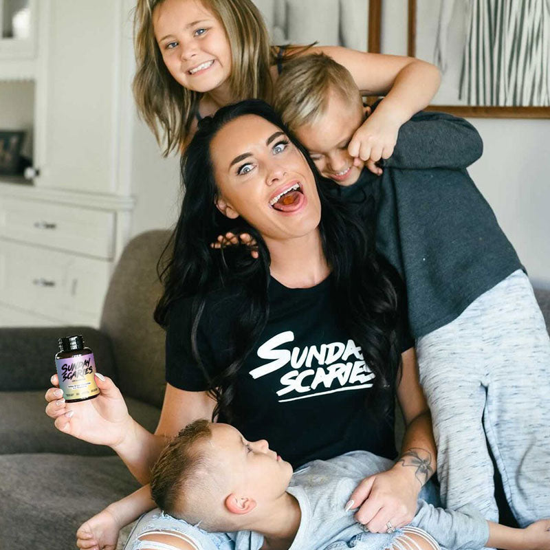A mom wrestles with the stress of three kids while eating a Sunday Scaries delta-9 gummy and holding the bottle