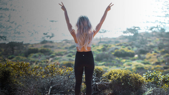 A woman free from migraines admires the view with her hands in the air 