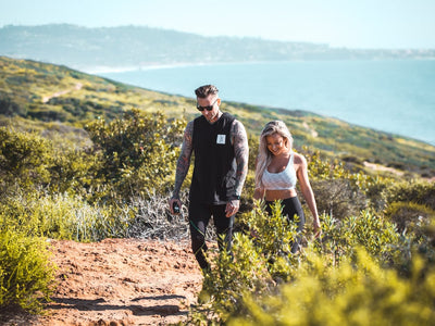 A male and female couple hike up a mountain by the sea