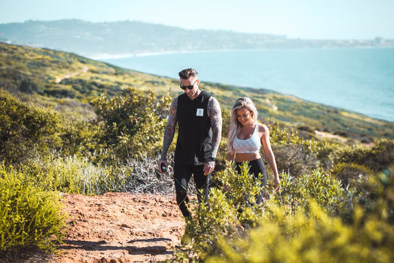 A male and female couple hike up a mountain by the sea