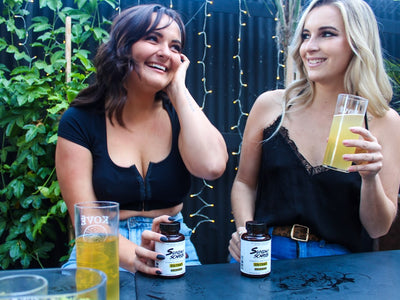 Two friends sit next to each other drinking kombucha and holding Sunday Scaries Extra Strength CBD Gummies