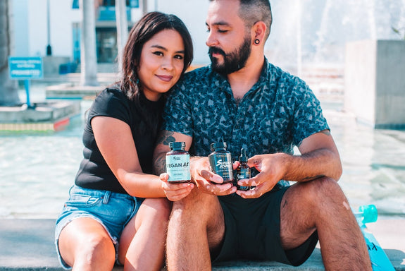 A couple sits down together holding Sunday Scaries products while the male looks at his girlfriend
