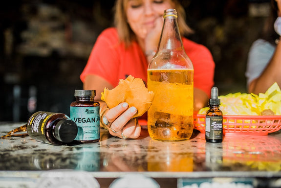 A female eats a burger and drinks a beer next to her CBD products