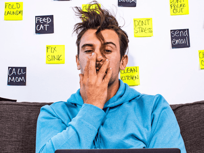 A man is covering his mouth while stressed on his computer
