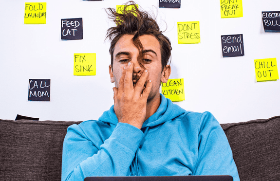 A man is covering his mouth while stressed on his computer