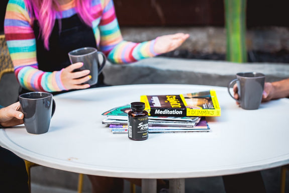 Three people drink coffee and talk about the book Meditation for Dummies around a table