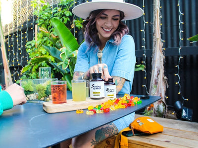 A woman holds a bottle of Sunday Scaries showing her friend what CBD does in THC edibles