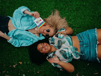 Two ladies lay down on the ground with cannabis products showing the difference between CBD vs CBN