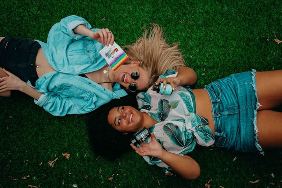 Two ladies lay down on the ground with cannabis products showing the difference between CBD vs CBN