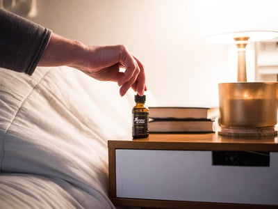 A man grabs a bottle of Sunday Scaries on his nightstand showing CBD vs THC for Sleep and which is better