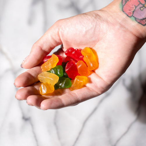 A woman holds a bunch of CBD gummies in her palm showing whether they have THC or not