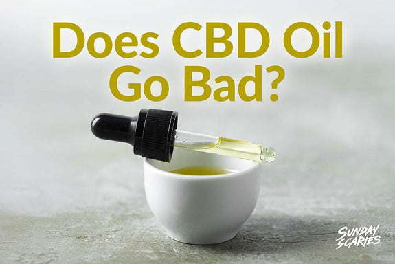 A pipette laying across a cup of yellow oil showing expired CBD oil
