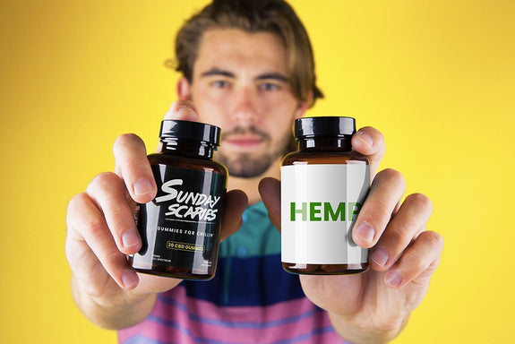 A man holds up two bottles showing hemp gummies vs. CBD gummies and what the difference is