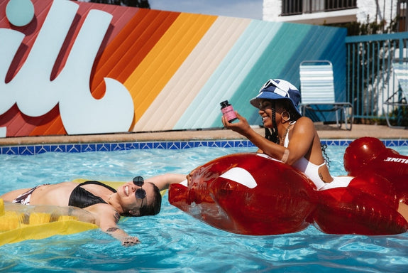 Two woman relax in the pool looking calm and happy, showing how CBD gummies make you feel