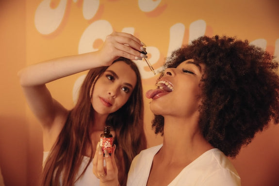 A female drops some Big Spoon in her girlfriend's mouth showing how long CBD oil takes to work for sleep