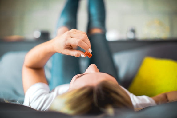 A woman lays back on her bed contemplating how long Delta-9 gummies last