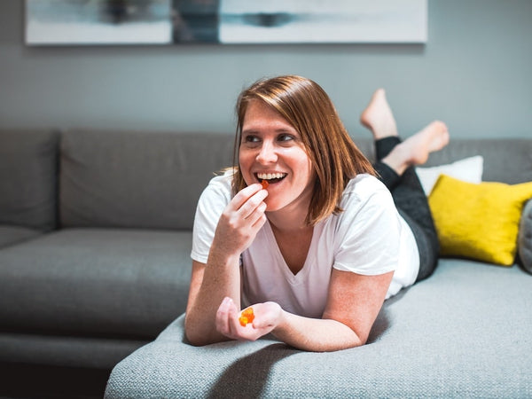 A woman lays down on her couch wondering how many CBD gummies to eat