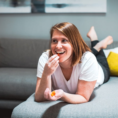 A woman lays down on her couch wondering how many CBD gummies to eat