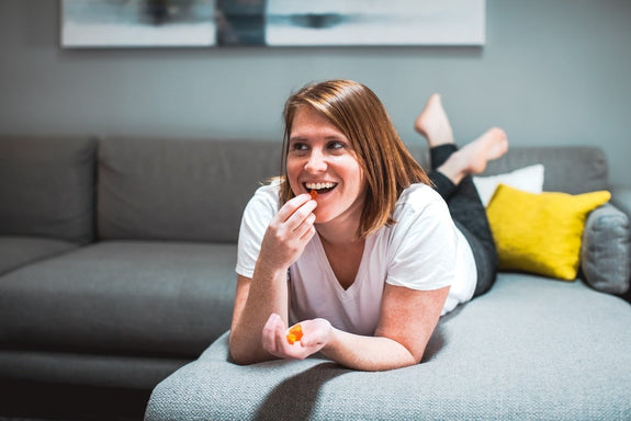 A woman lays down on her couch wondering how many CBD gummies to eat