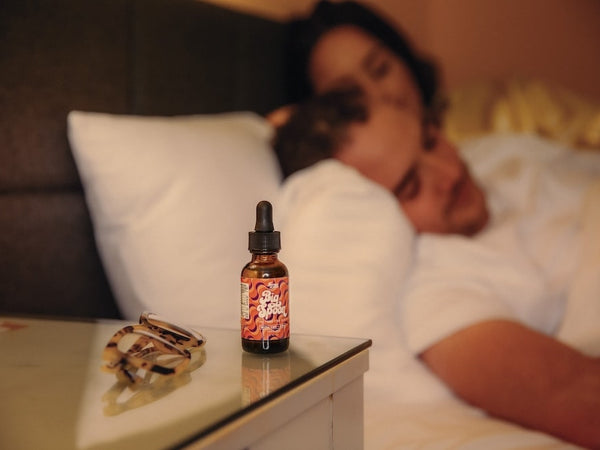 A bottle of Big Spoon sits on the nightstand of a couple after they consider how much CBD oil to take for sleep