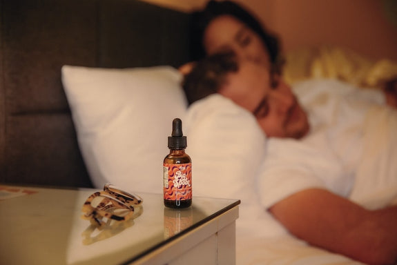 A bottle of Big Spoon sits on the nightstand of a couple after they consider how much CBD oil to take for sleep