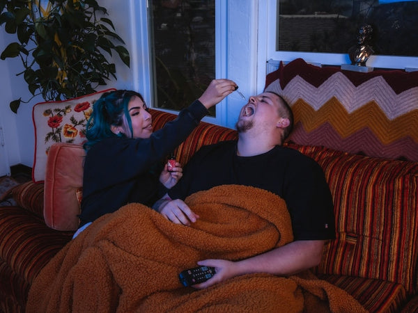 A girlfriend shows her boyfriend how to use CBD oil for sleep before bedtime