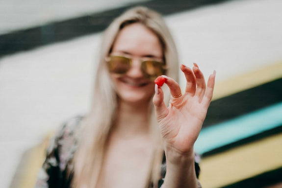 A woman holds up a gummy to show what CBD edibles are