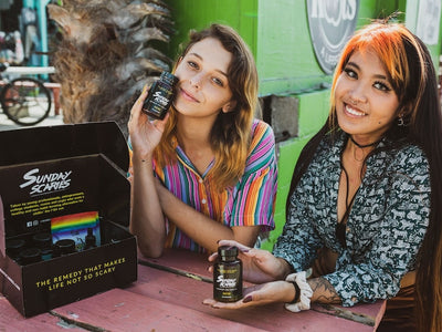 Two girls hold up Sunday Scaries CBD gummies showing what CBD edibles do