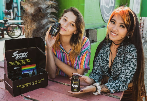 Two girls hold up Sunday Scaries CBD gummies showing what CBD edibles do