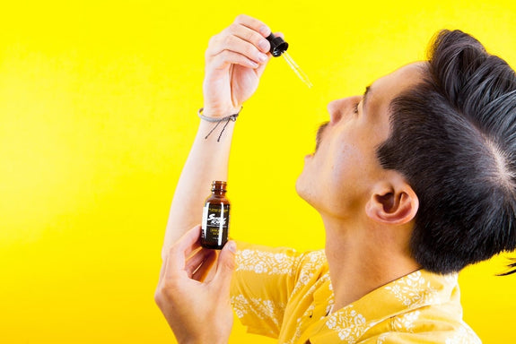 A man drops a pipette of CBG oil in his mouth showing how to use CBG (Cannabigerol)