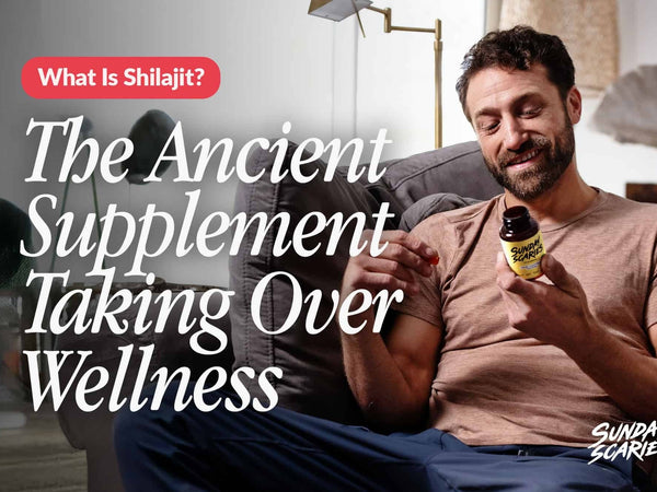 A man looking at the back of a Sunday Scaries Shilajit gummies bottle while sitting on the couch. 
