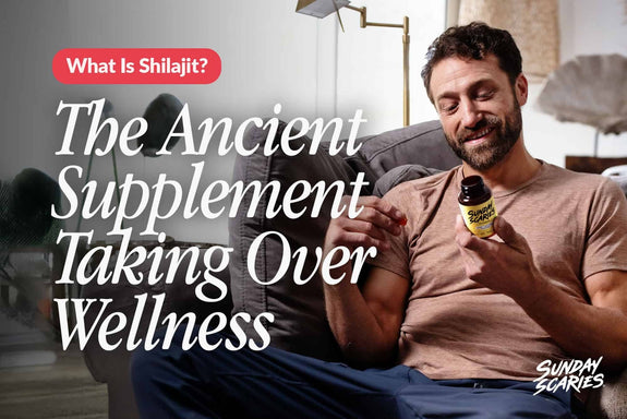 A man looking at the back of a Sunday Scaries Shilajit gummies bottle while sitting on the couch. 