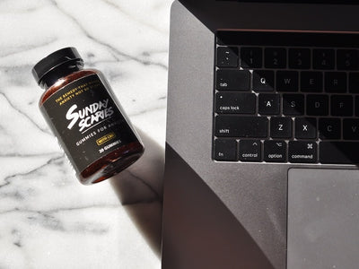 A bottle of Sunday Scaries CBD gummies lays next to a computer showing users they can buy CBD edibles online