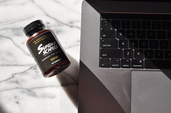 A bottle of Sunday Scaries CBD gummies lays next to a computer showing users they can buy CBD edibles online