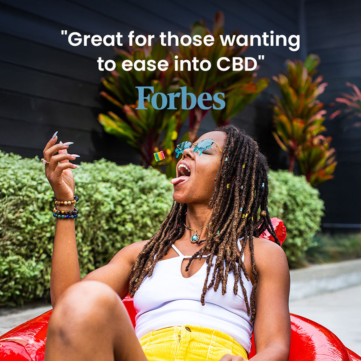 Person relaxing in a red chair with a quote from Forbes that reads "Great for those wanting to ease into CBD"
