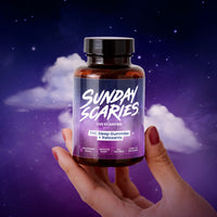 A hand holding up the Sunday Scaries THC Sleep gummies bottle on a starry night background