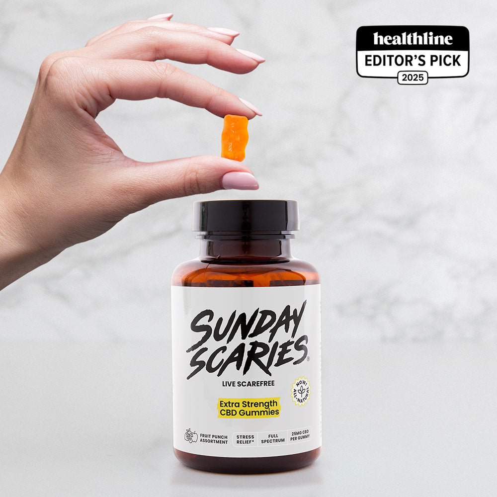 Hand holding a Sunday Scaries CBD gummy next to a bottle on a light gray background
