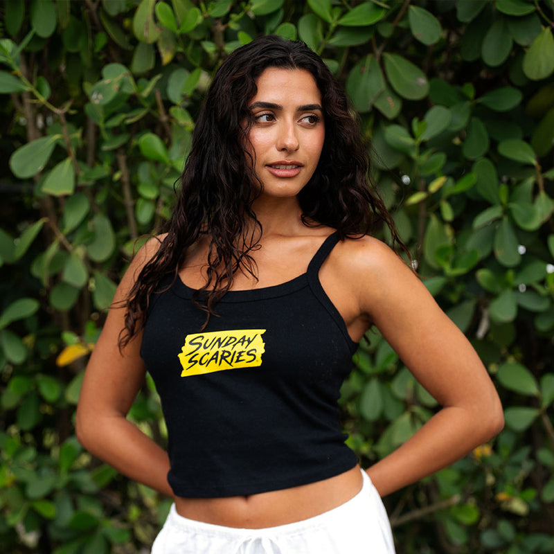 A woman wears the sunday scaries tank top outside